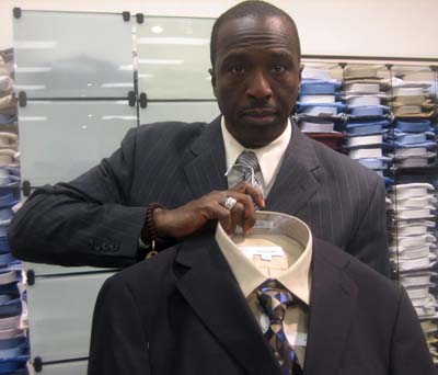 David Melton, assistant store manager at the Men's Warehouse in Silver Spring, holds up a more formal alternative outfit for those seeking jobs as educators or in techonology, Newsline photo by Alan J. McCombs